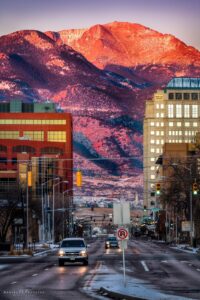 Downtown Colorado Springs with Colorado Avenue leading towards a Glowing red Pikes Peak mountain in the background. 